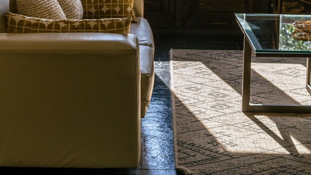 A room with a sofa, a glass coffee table, and a view through a window with curtains. - Hotel Newen BnB (Pucón)
