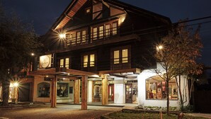 A two-story wooden building with a balcony, a shop on the ground floor, and a visible entrance. - Hotel Newen BnB (Pucón)