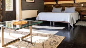 A bedroom with a bed, a glass table, a woven rug, and a wooden ceiling. - Hotel Newen BnB (Pucón)
