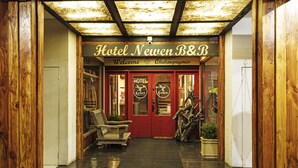 The entrance to Hotel Neuer B&B with a red door, wooden interior, and a welcome sign. - Hotel Newen BnB (Pucón)