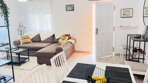 Een moderne woonkamer met een bank, salontafel en eettafel.