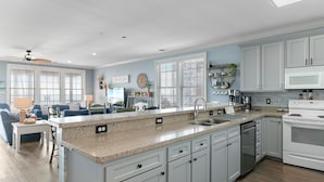 A spacious kitchen with white cabinets, a granite countertop, and a built-in dishwasher.