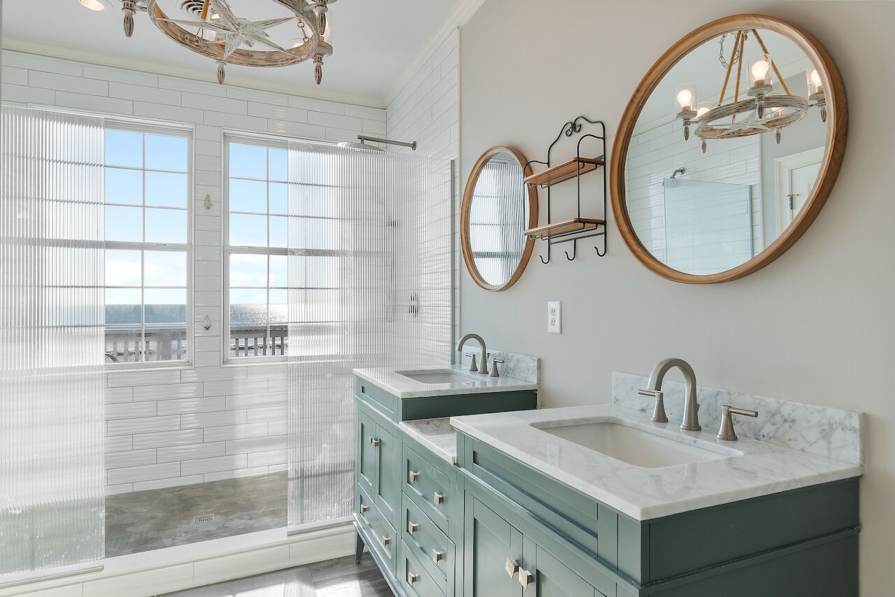 Une salle de bain avec deux lavabos, un grand miroir et un lustre.