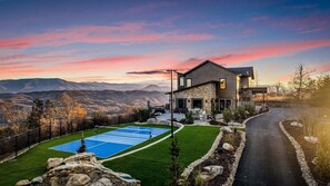 Une maison moderne avec une façade en pierre, une piscine et une vue sur les montagnes.