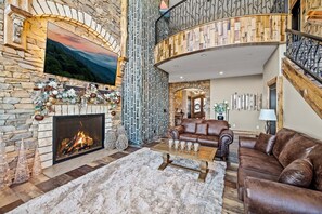 A stone fireplace, a leather sofa, and a wooden staircase.