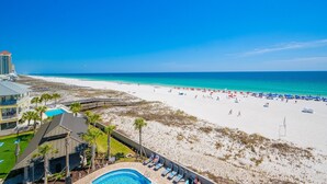 Un complexe hôtelier en bord de mer doté d’une piscine, de parasols et offrant une vue sur l’océan.