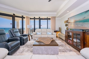 Una sala de estar con sofá, sillones, una mesa de centro y televisor.