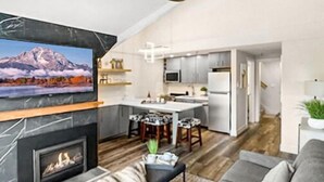 Un salon moderne avec une cheminée, un canapé et un téléviseur.