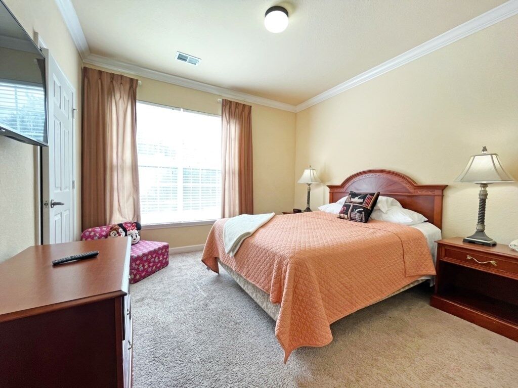 Une chambre à coucher avec un lit, des lampes de chevet, une commode et une fenêtre avec des rideaux.