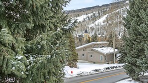 A snow-covered landscape with a building that appears to be a lodge or hotel, surrounded by trees and a clear sky.
