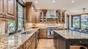 A spacious kitchen with wooden cabinets, granite countertops, a large island, and a stone backsplash. - 4418 Columbine Drive 4 Bedroom Home by RedAwning (Vail)