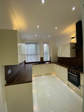 A modern kitchen with white cabinets, a dark countertop, and a built-in oven. - Charming 2-bed Apartment in Wolverhampton (Wolverhampton)