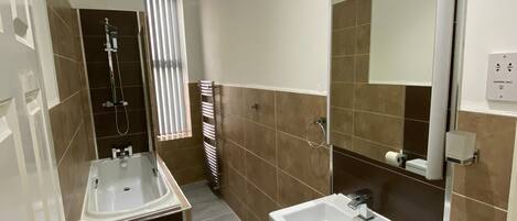 A modern bathroom with a shower, two sinks, a toilet, and a mirror.
