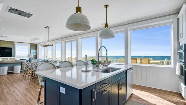 Una cocina moderna con una isla grande, encimeras blancas y vistas al océano.
