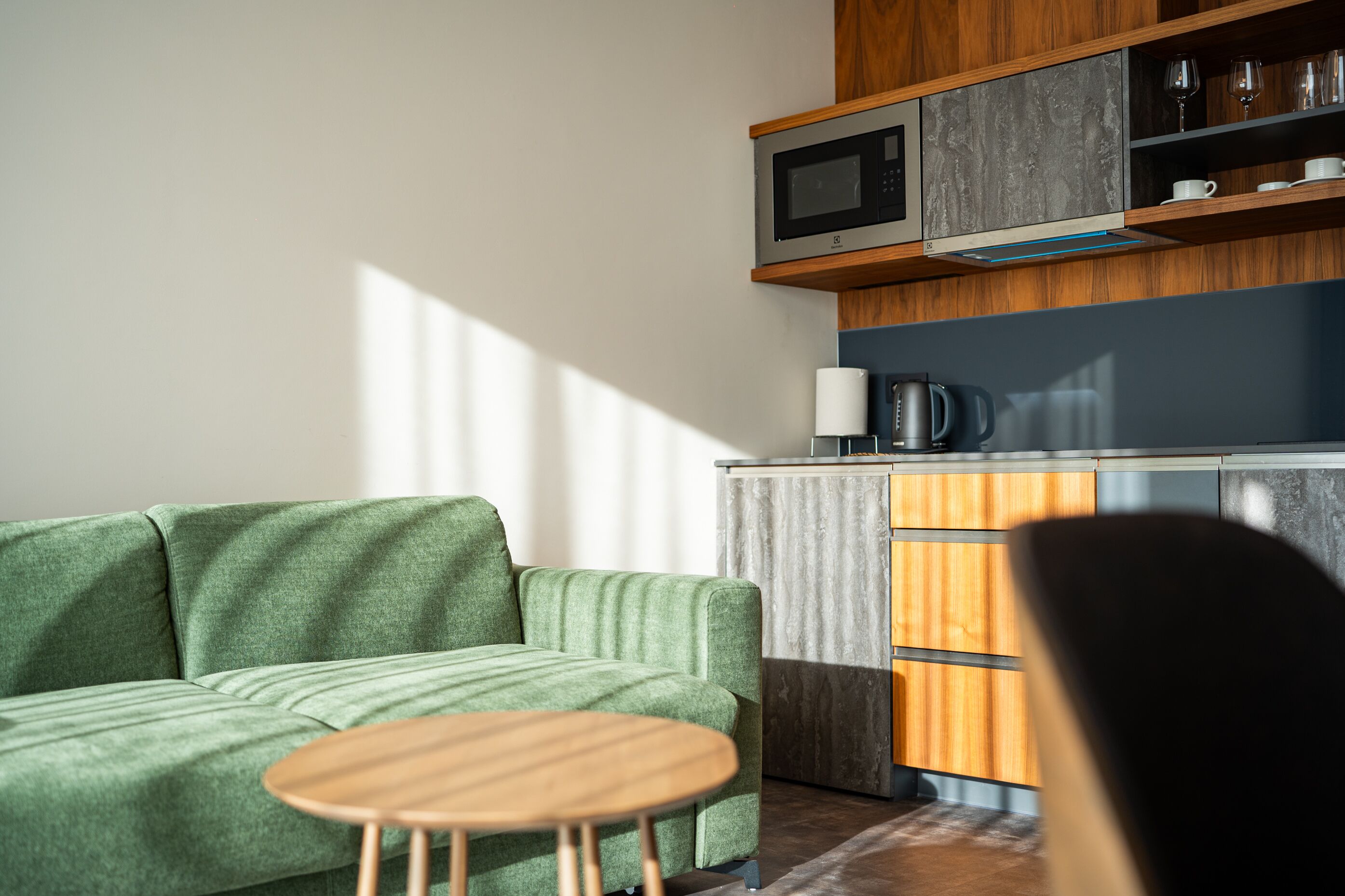 A modern living room with a green sofa and a wooden coffee table.