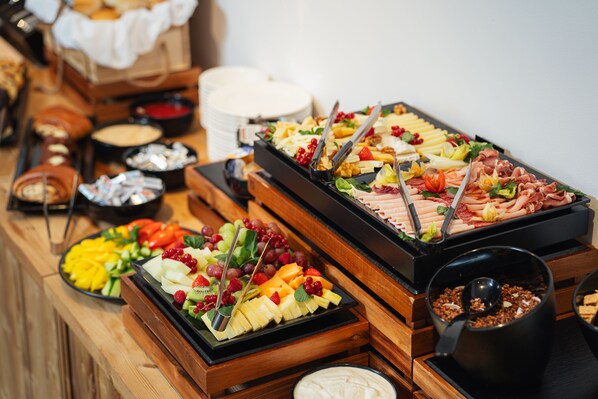 A buffet with various food items including fruits, cheeses, and meats.