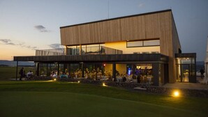 A modern building with a flat roof, large windows, and a covered outdoor seating area. - Royal Village (Malý Slavkov)