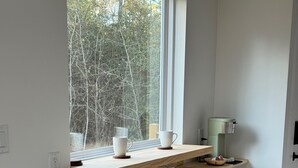 A small kitchen area with a window, two stools, a coffee machine, and a bowl on a shelf. - Luxury Cabin - Riolago (Montgomery County)