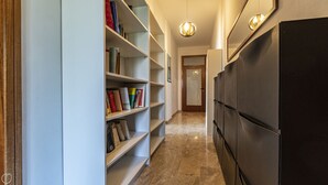 Un pasillo con una estantería, un refrigerador negro y una puerta al final.