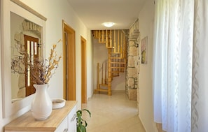 Staircase leads to a beautifully appointed hallway with a console table, mirror, and potted plant.
