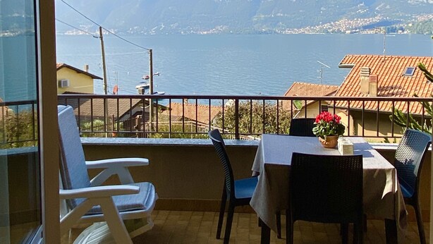 A balcony with a table and chairs, overlooking a mountainous landscape and a body of water. - Sofia apartment near Bellagio (Lezzeno)