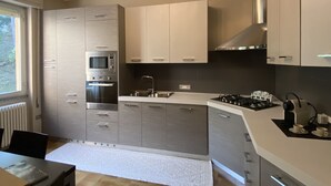A modern kitchen with built-in appliances, a gas stove, and a window providing natural light. - Sofia apartment near Bellagio (Lezzeno)