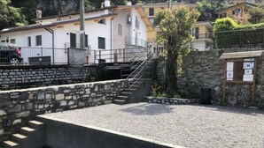 A stone retaining wall with a concrete platform, a metal staircase, and a small tree. - Sofia apartment near Bellagio (Lezzeno)