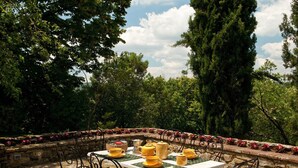 An outdoor dining area with a table set for four, surrounded by stone walls and lush greenery.