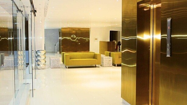 A modern lobby with a glass wall, a yellow sofa, and a reception desk. - Hotel Layalee Grande Chennai (Chennai)