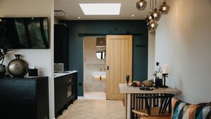 Una cocina moderna con piso de espiga, una puerta de madera y un área de comedor con una mesa lista para dos.