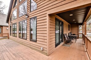 A wooden cabin with a covered porch, large windows, and a dining area with outdoor seating. - Stepaway Vacation Rentals-LCR#3 (St. Germain)