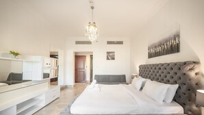 A modern bedroom with a large bed, a TV, and a chandelier. - Stylish Urban 1BR Gem in Fairmont-90AB2 (Dubai)