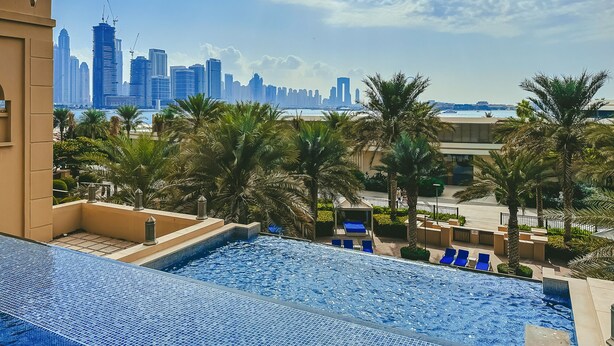 A rooftop pool with a view of a city skyline and palm trees. - Stylish Urban 1BR Gem in Fairmont-90AB2 (Dubai)
