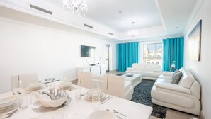 A modern living room with a dining area, white furniture, and a view of the city. - Stylish Urban 1BR Gem in Fairmont-90AB2 (Dubai)