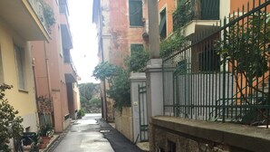 Uma rua estreita ladeada por edifícios com varandas e uma grade de metal.