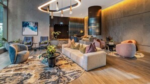 A modern lobby with a central seating area, a large abstract painting, and a unique circular light fixture. - CBD, Stylish, Heated Pool, Gym, Sauna, Steam, BBQ (Melbourne)