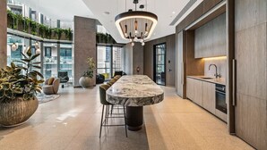 A modern kitchen with a marble island, pendant lighting, and a view of the city. - CBD, Stylish, Heated Pool, Gym, Sauna, Steam, BBQ (Melbourne)