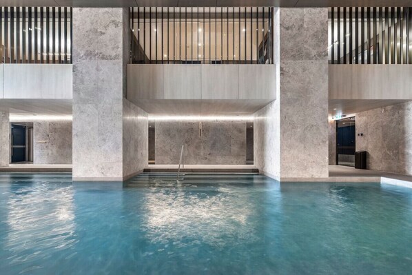 A spacious indoor pool with a clear view of the surrounding architecture, including a high ceiling and a mezzanine level.