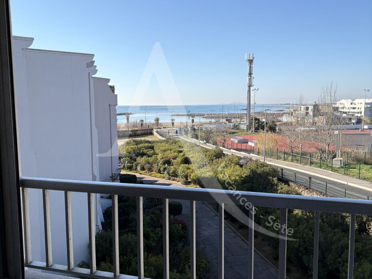 A balcony with a view of a coastal area, including a marina and buildings.