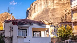 Un edificio de dos pisos con una escalera de piedra que conduce a la entrada, frente a una gran formación rocosa.