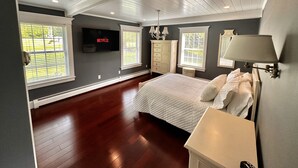 A bedroom with a large bed, a TV mounted on the wall, and a window with blinds. - The Cozy Goshen Home, 5mins from LEGOLAND and near skiing! (Goshen)