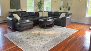 A spacious living room with a sectional sofa, a round coffee table, and a large rug. - The Cozy Goshen Home, 5mins from LEGOLAND and near skiing! (Goshen)