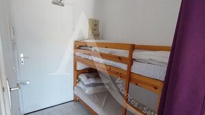 A room with a bunk bed, a door with a handle, and a light switch on the wall. - STUDIO DANS RESIDENCE AVEC ASCENSEUR, PLAGE A PIED (Sète)
