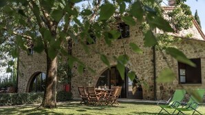A stone building with a dining area featuring a table and chairs, surrounded by a well-maintained lawn.