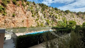 A swimming pool with a view of a rocky hillside and trees. - T3 sur les hauteurs dans résidence avec piscine (Sète)