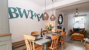 Un espace repas avec une grande table, des chaises en bois et un panneau fixé au mur.