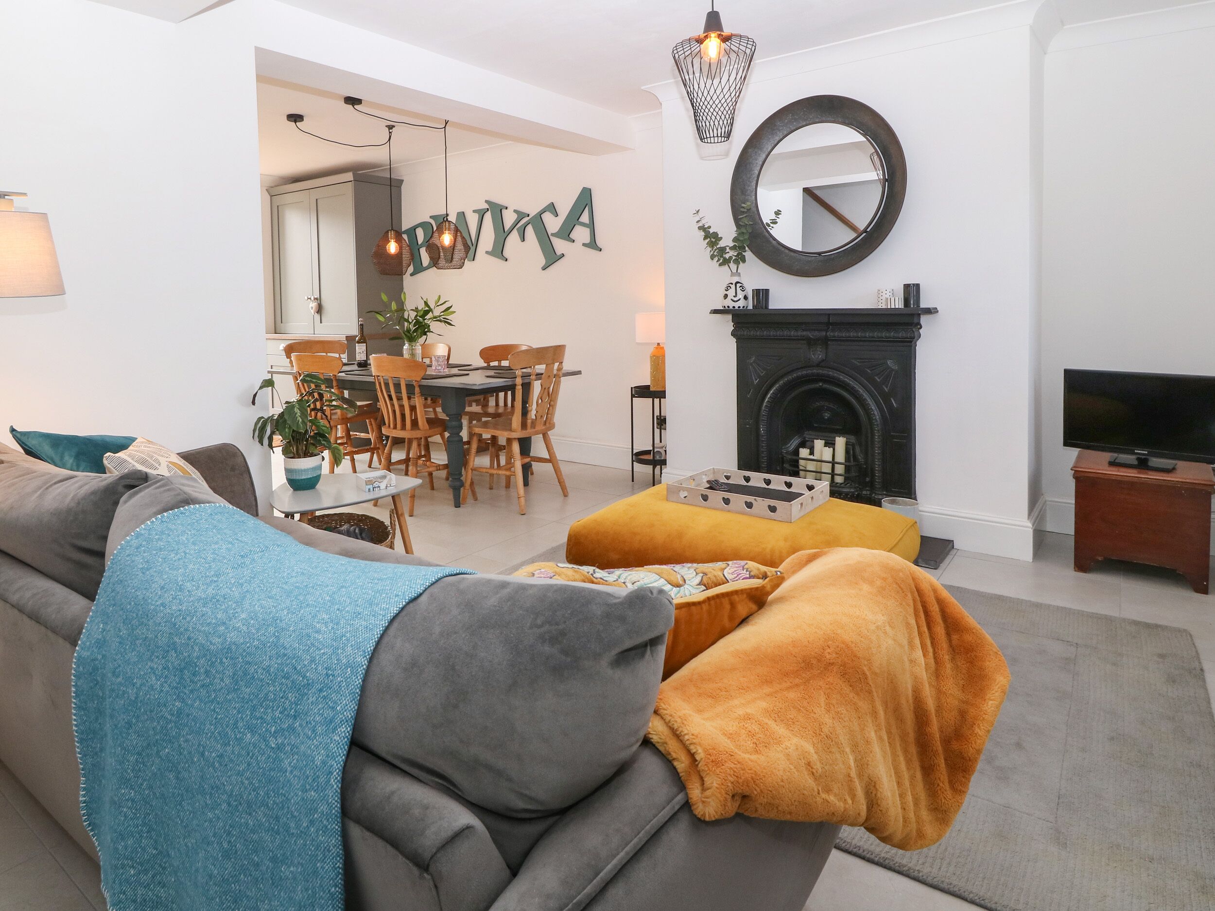 Ein modernes Wohnzimmer mit einer Couch, einem Hocker und einem Essbereich mit Stühlen und einem Tisch.