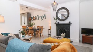 Un salon moderne comprenant un canapé, un pouf et un coin repas avec des chaises et une table.