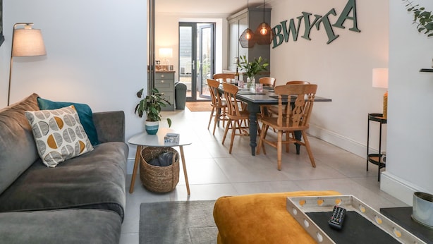 Un salon moderne comprenant un canapé, une table basse et un coin repas avec des chaises et une table en bois.