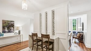 A dining area with a white table, two chairs, and a decorative wall panel. - NEW REMODEL Chalmers at the Historic Bryson Building (Savannah)